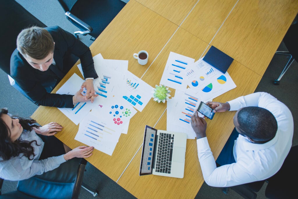 Team discussing data charts around conference table.