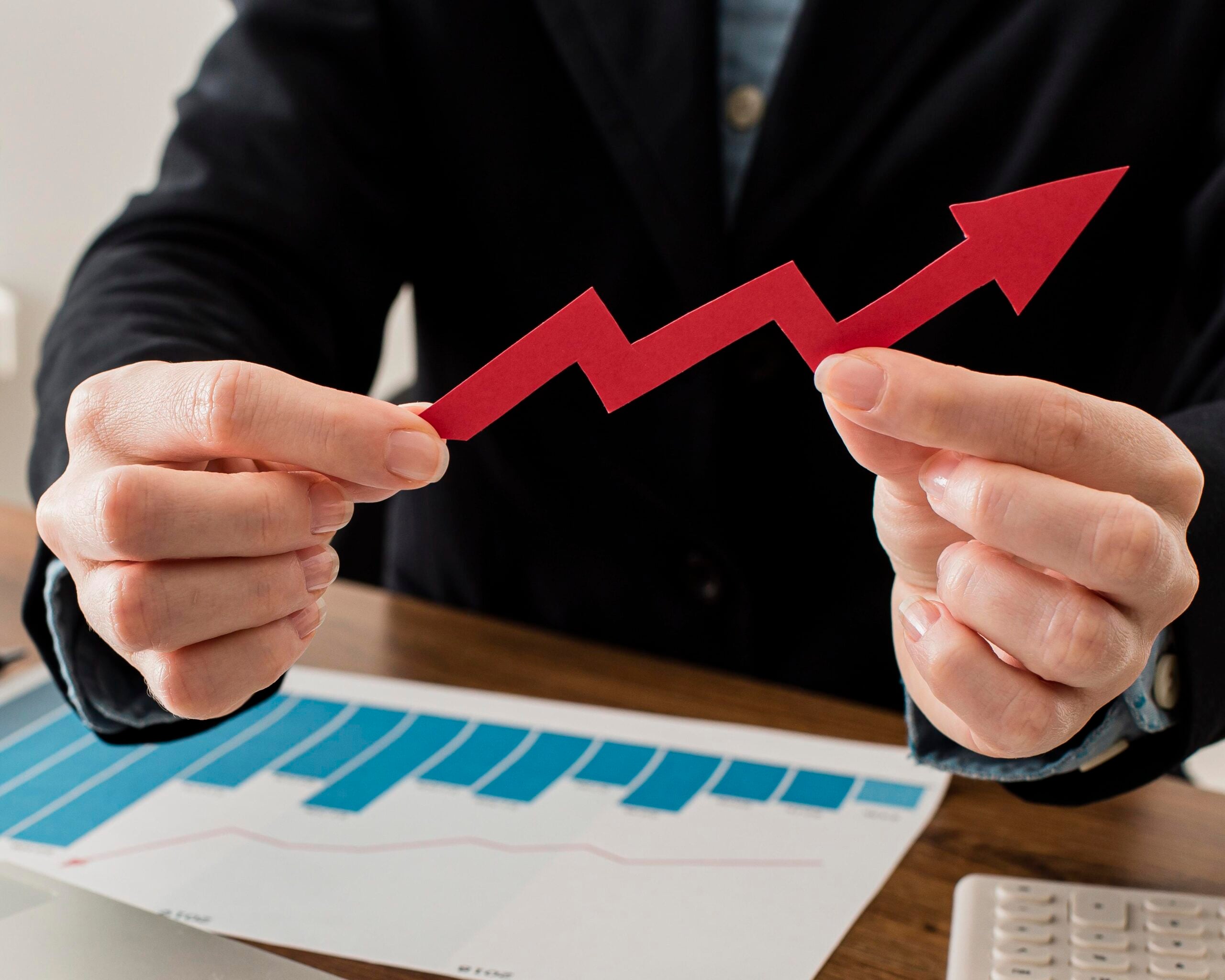 Person holding upward trending arrow, business growth concept.