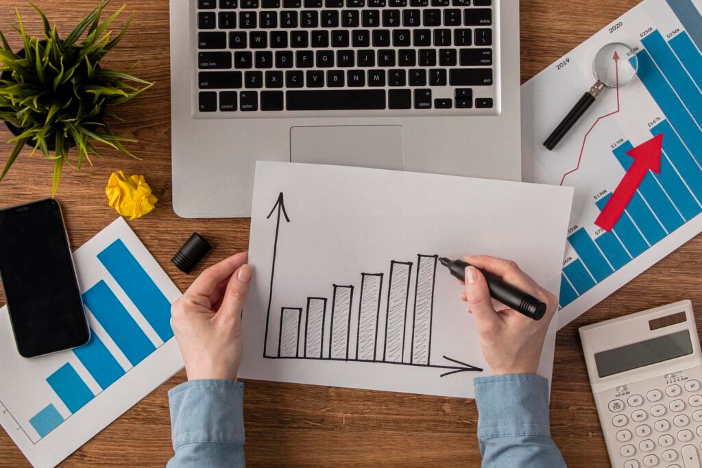 Person sketching business growth charts at desk
