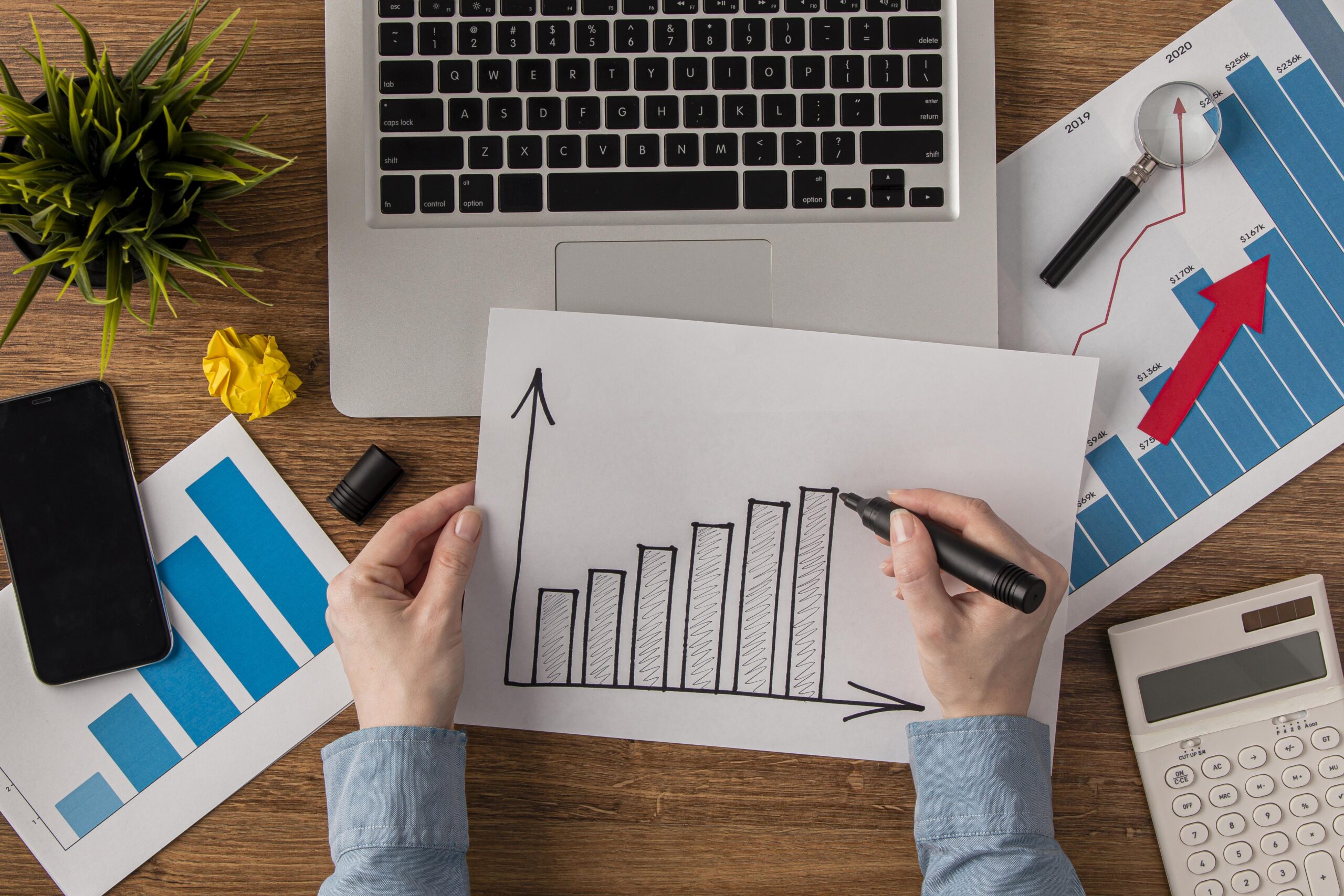 Person sketching business growth charts at desk