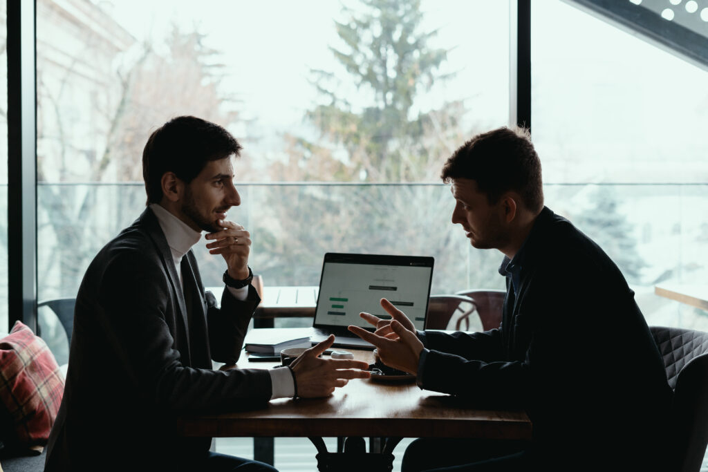 Two men discussing business at a table indoors.