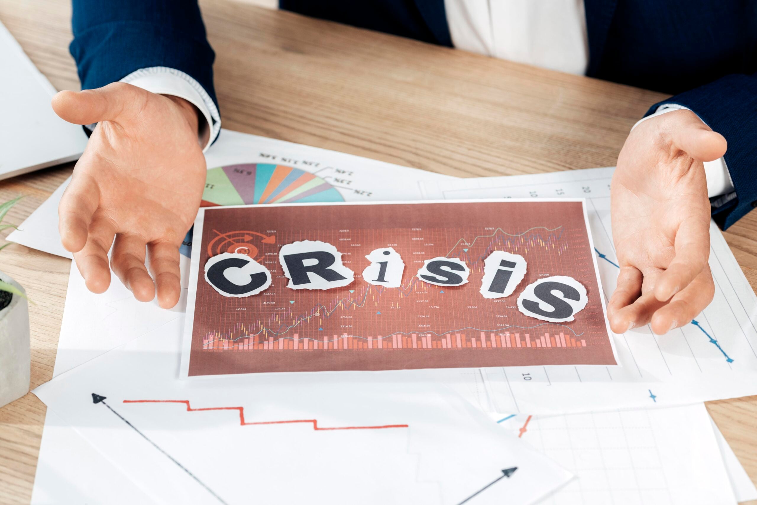 Businessman discussing financial crisis graph on table.
