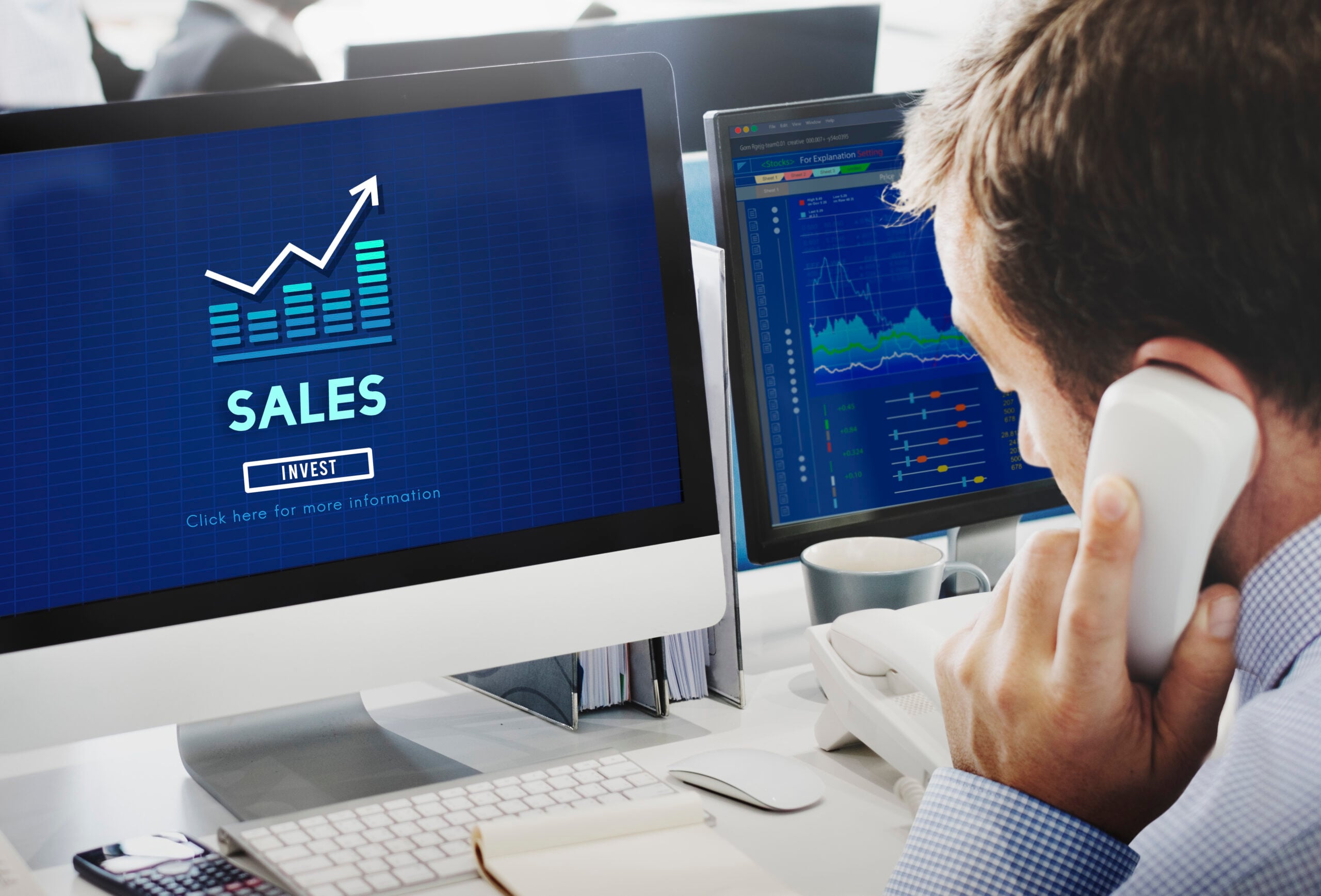 Businessman analysing sales data on computer screens.